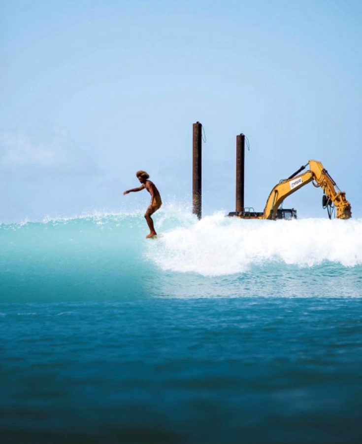 Waikiki surfer catching a wave in front of American Marine sand replenishment project