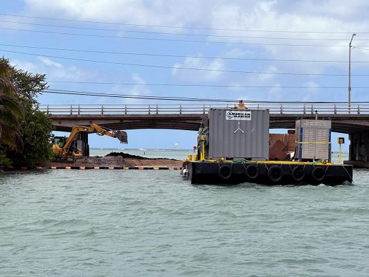 barge with excavator working at private marine Hawaii Kai in Oahu dredging under the entrance channel